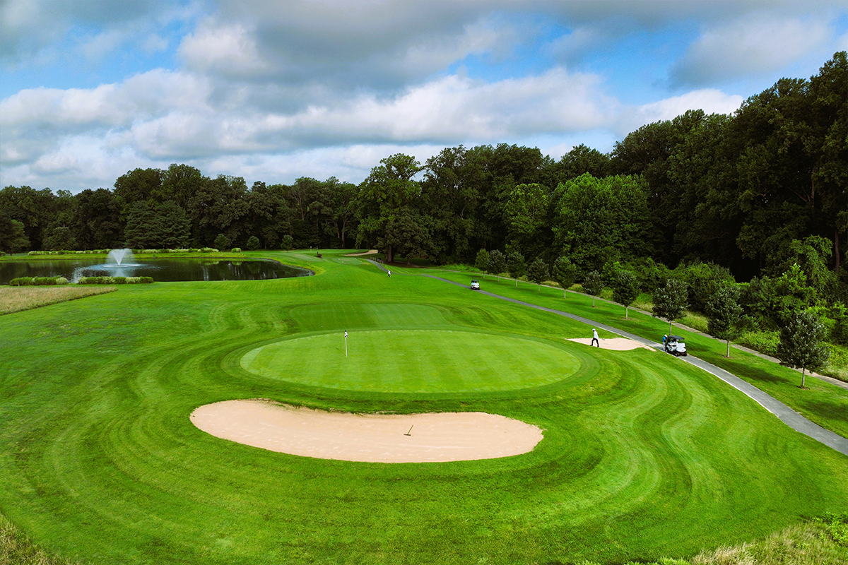 Hole 4 at Enterprise Golf Course. There is a bright green circle around the hole, and a sand trap off to the side.