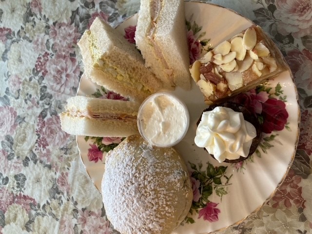 An assortment of sandwiches and pastries on a plate with a floral pattern.