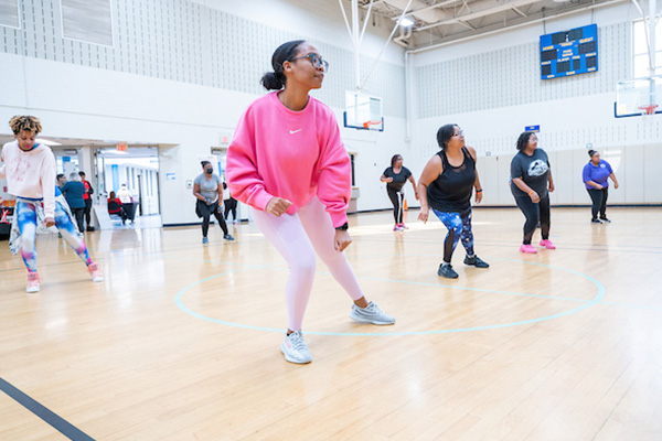 Adults in workout clothes doing aerobics in a gym.